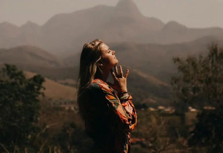 a woman standing in front of a mountain range.