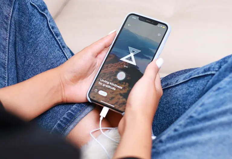 a person sitting on a couch holding a cell phone.