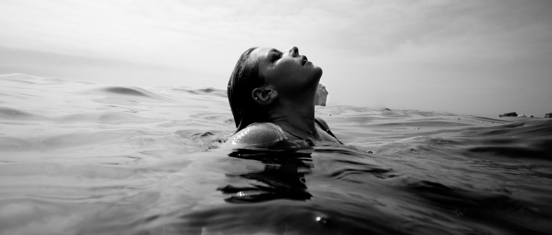 a woman floating in the ocean with her head above the water.