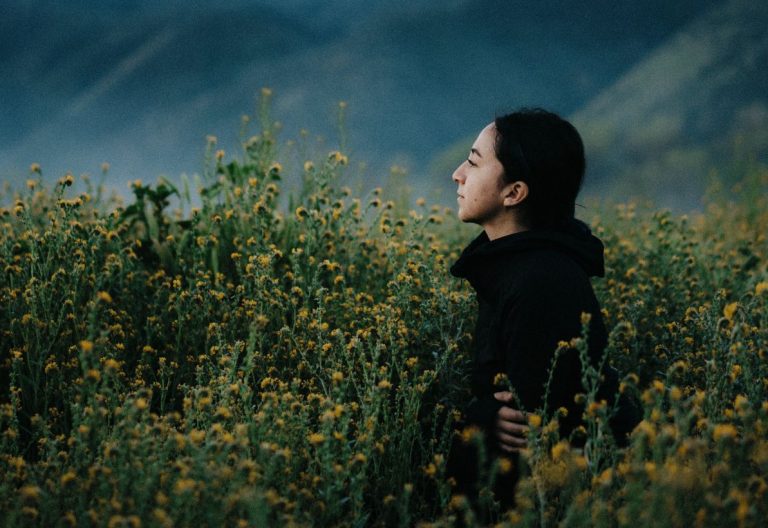 a woman standing in a field of yellow flowers.