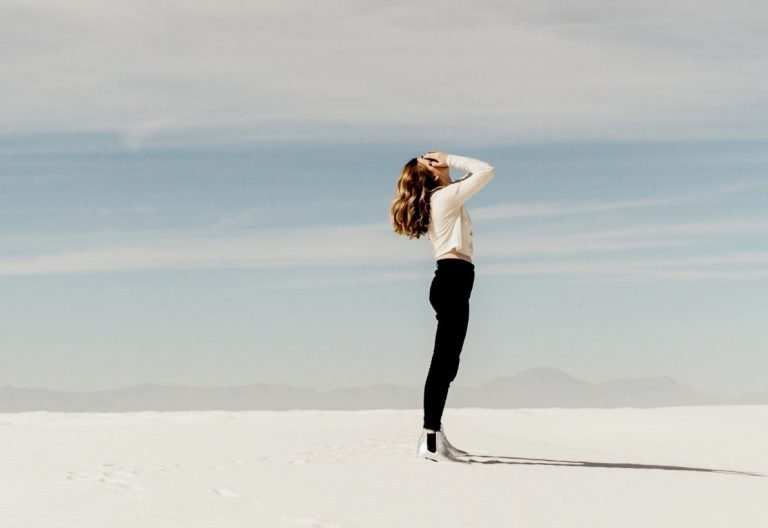 a woman standing in the middle of a desert.