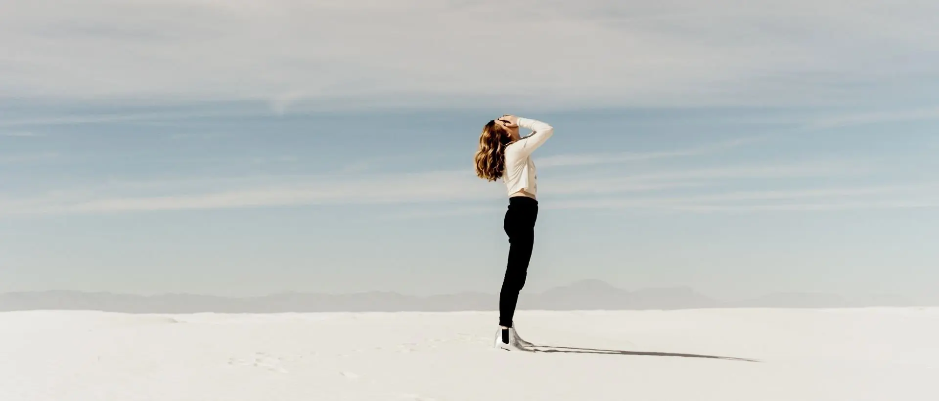 a woman standing in the middle of a desert.