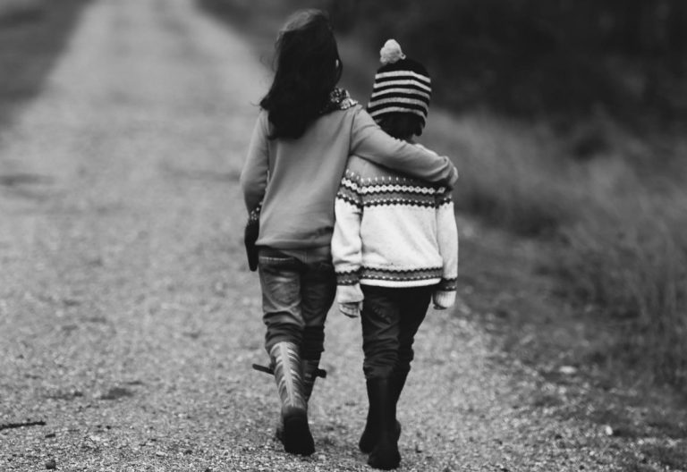 a couple of people walking down a dirt road.