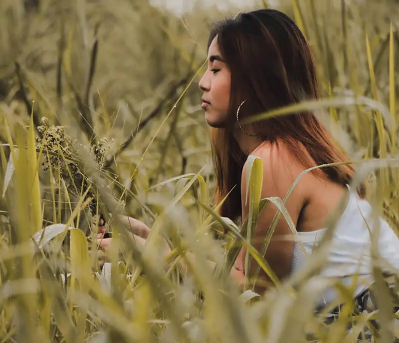 a woman sitting in a field of tall grass.