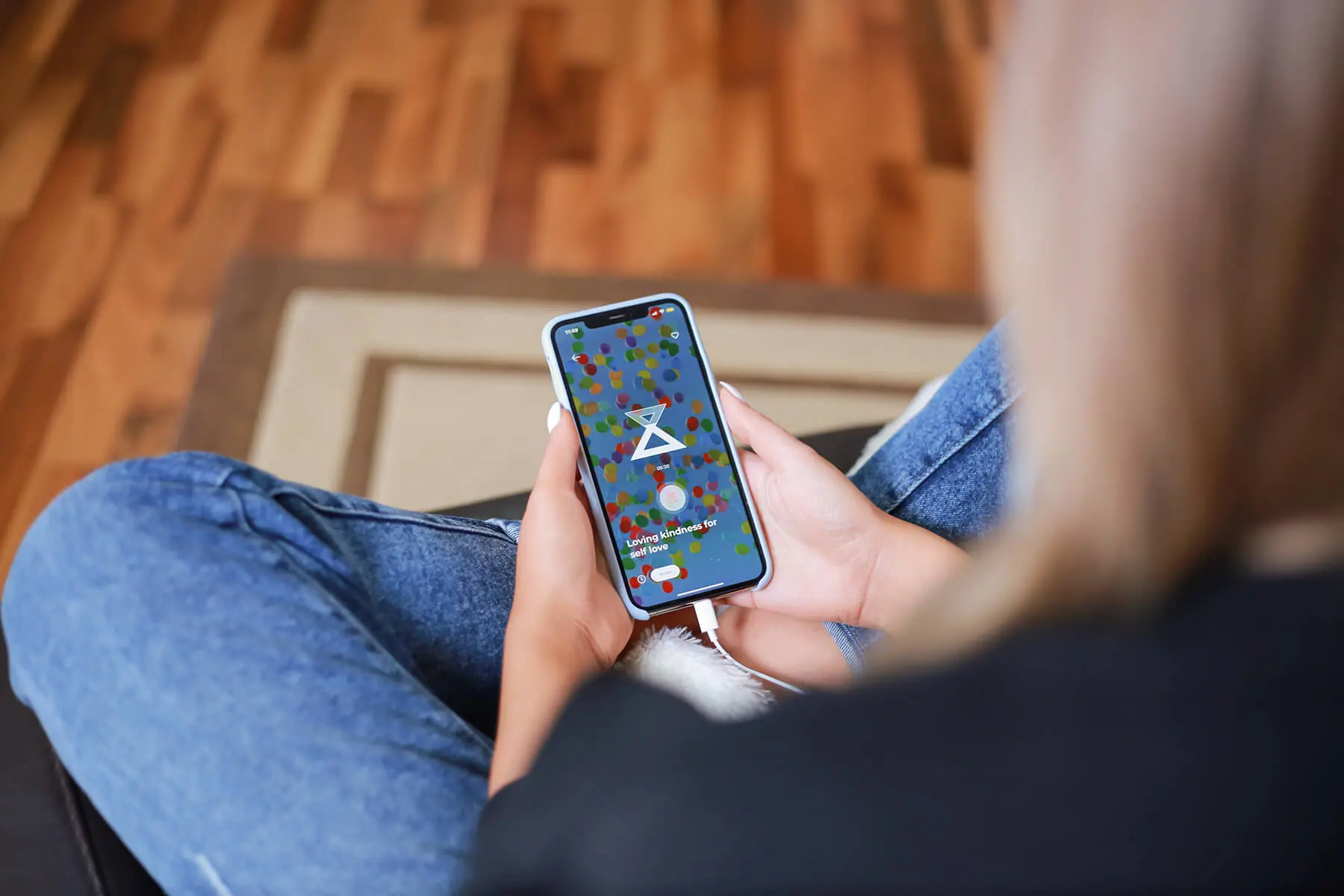 a woman sitting on a couch holding a cell phone.