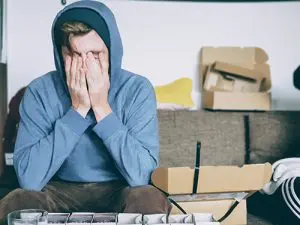 a man sitting on a couch with his hands covering his face.