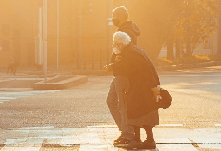 a woman with a child on her back crossing a street.