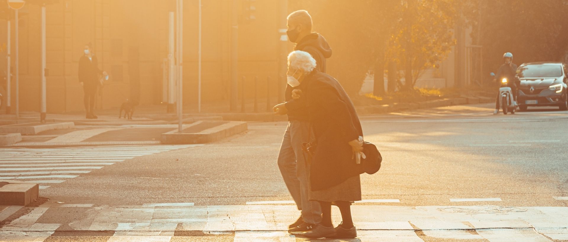 a woman with a child on her back crossing a street.