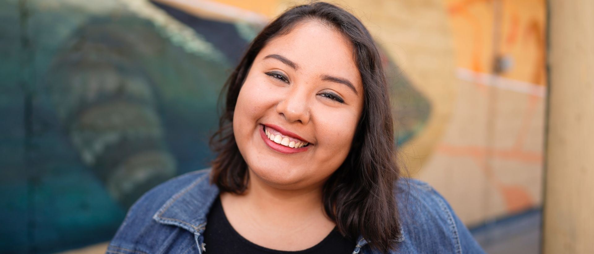 a woman smiling in front of a painting.