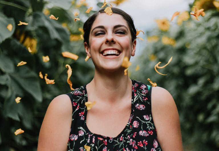 a woman standing in front of a field of sunflowers.