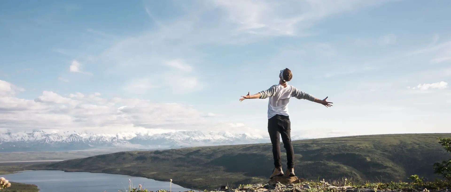 a man standing on top of a hill with his arms outstretched.