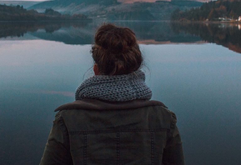 a woman standing in front of a body of water.