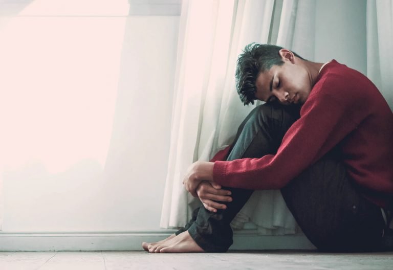 a man sitting on the floor in front of a window.