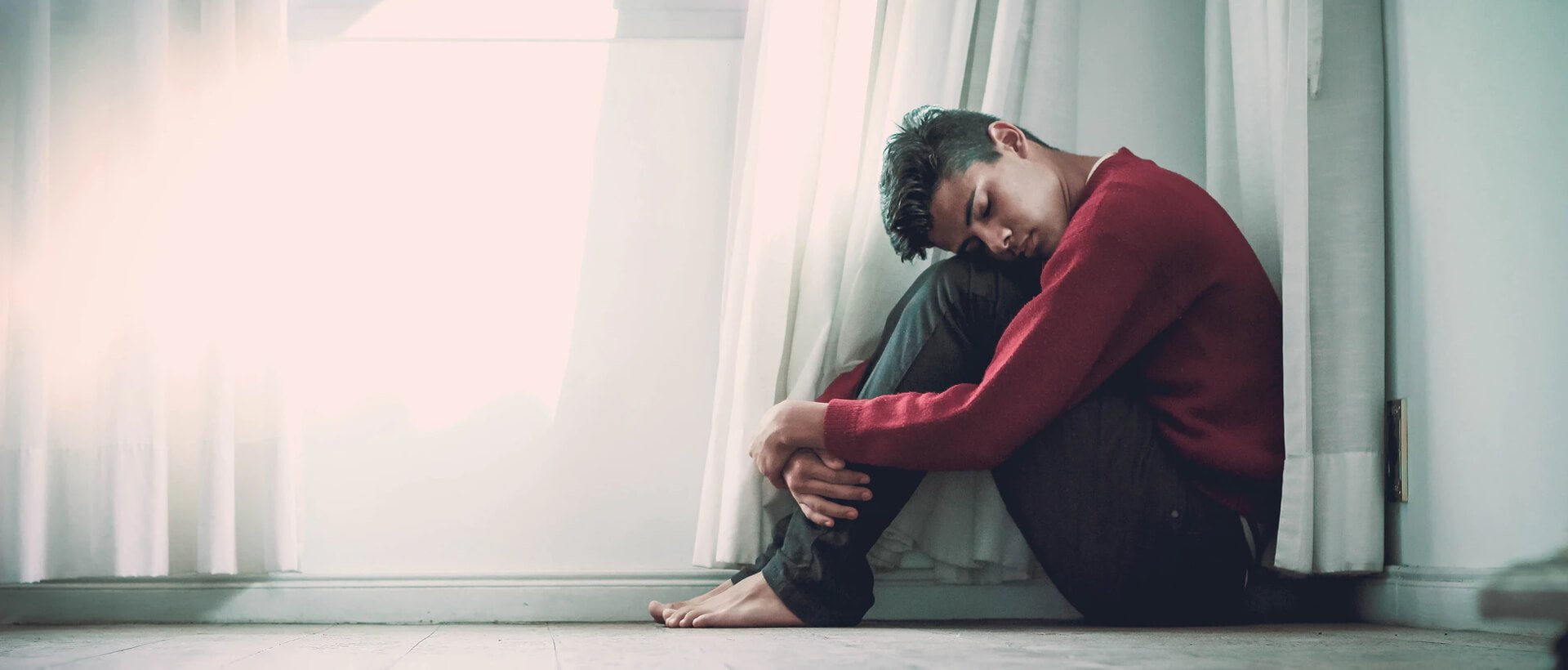 a man sitting on the floor in front of a window.