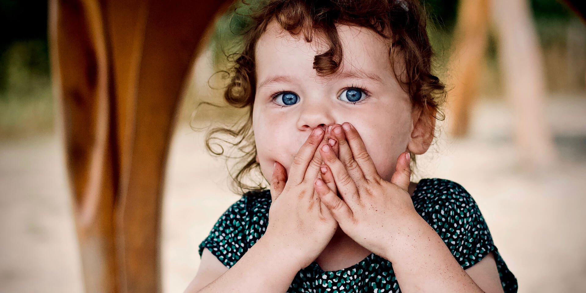 a little girl that is covering her mouth.