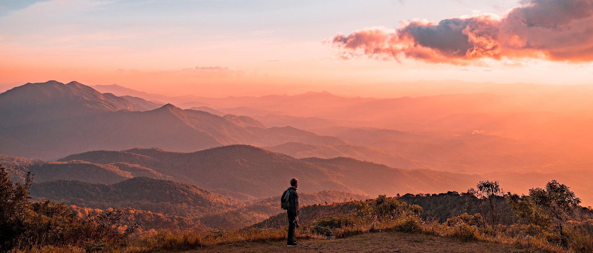 a man standing on top of a lush green hillside.