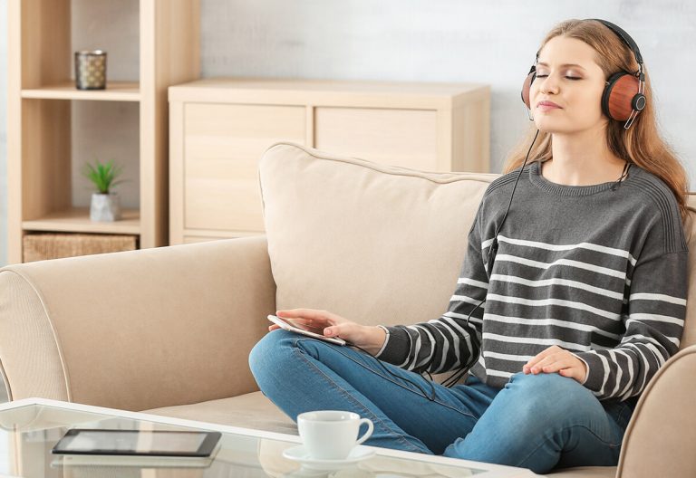 a woman sitting on a couch listening to music.