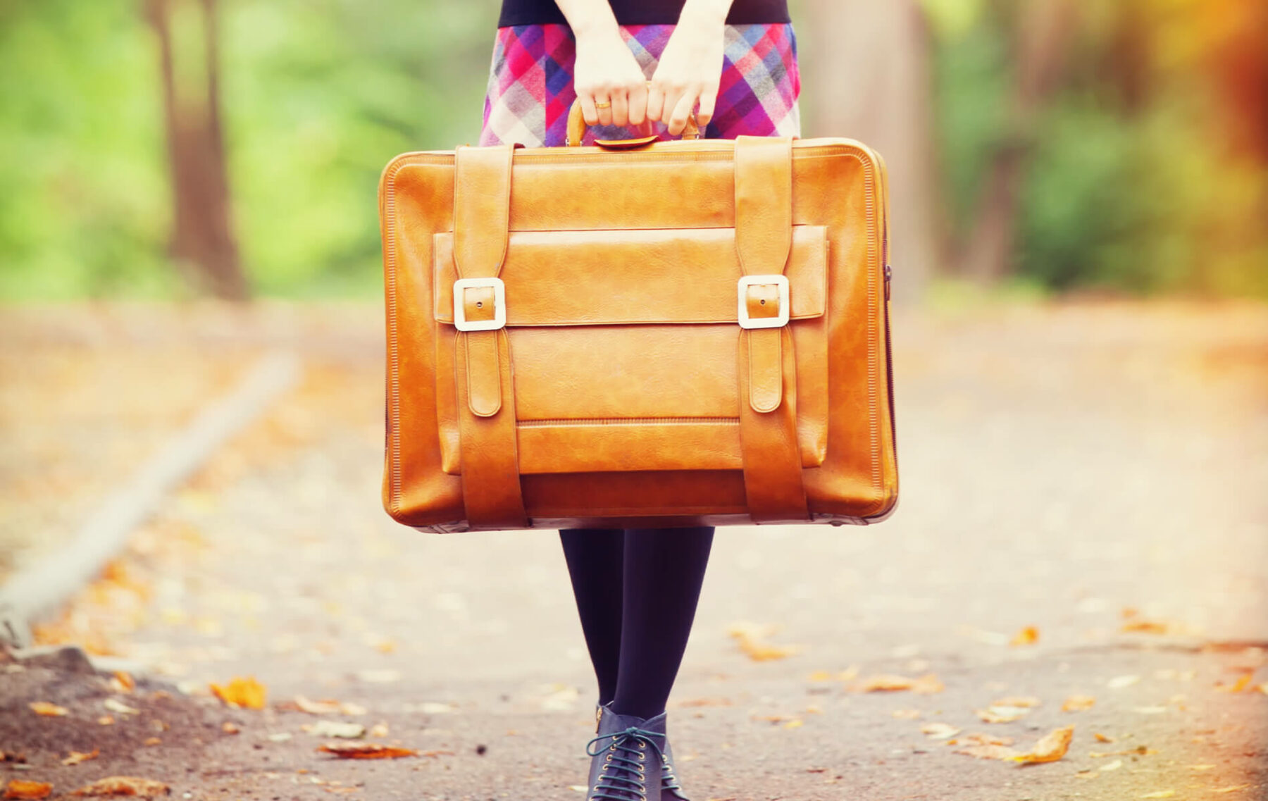 a woman carrying a brown briefcase down a road.