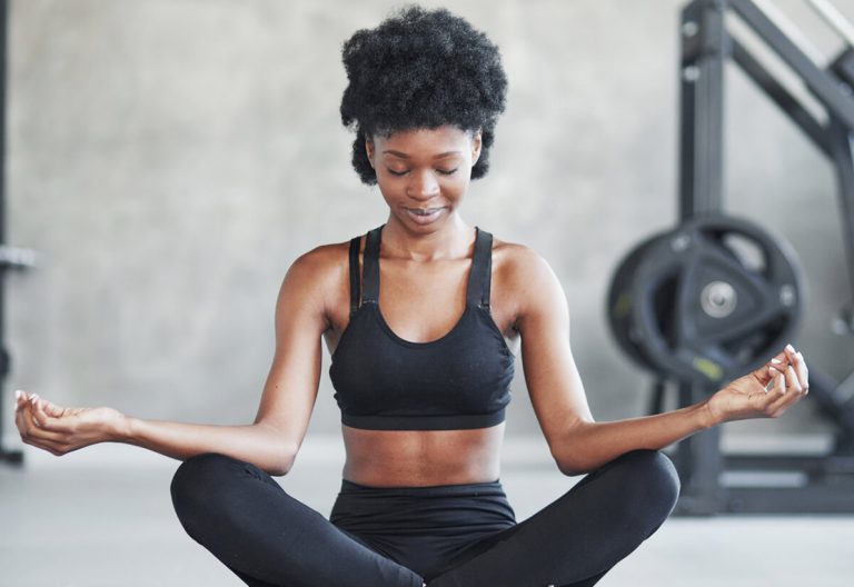 a woman sitting in a yoga position in a gym.