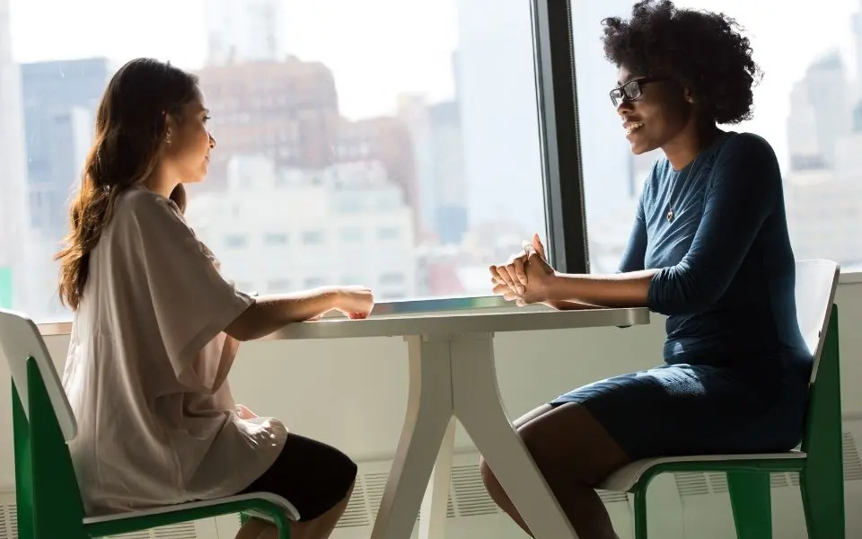 Two women in conversation seated at a table