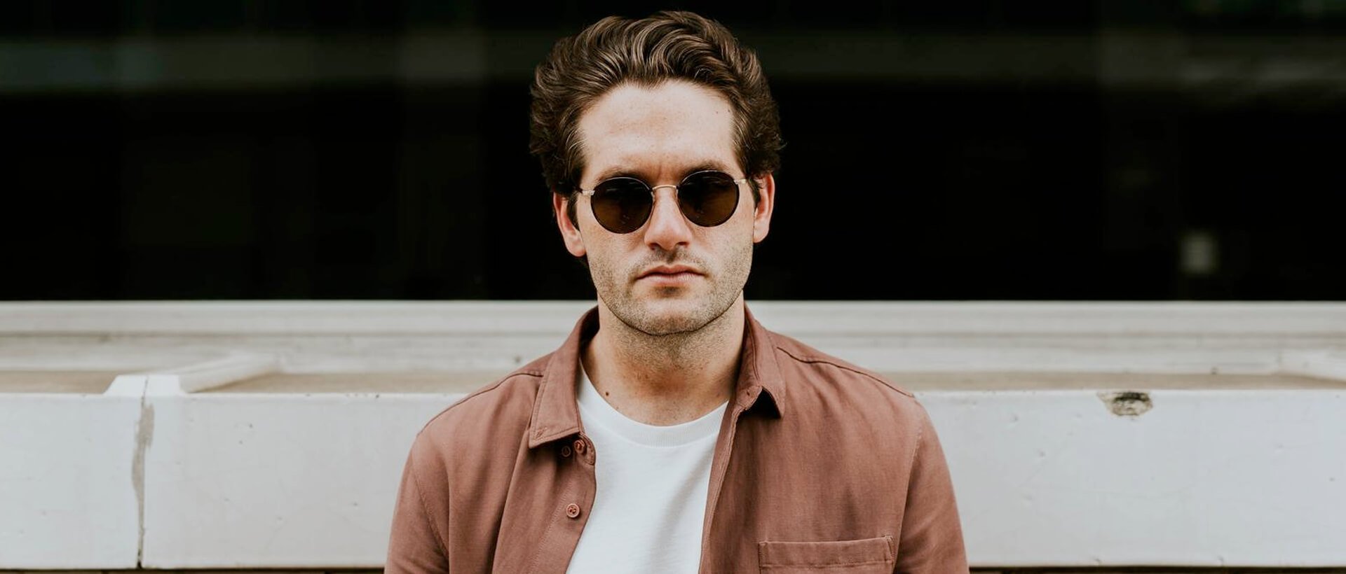 a man wearing sunglasses standing in front of a building.