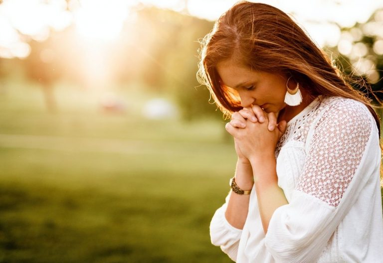 a woman standing in a field holding her hands to her face.