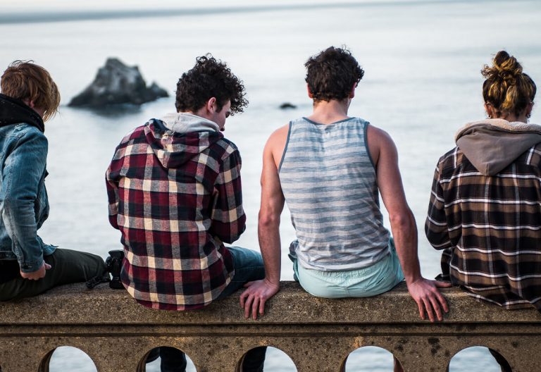 a group of people sitting on top of a stone wall.