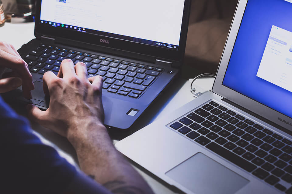 Man organizing his work on two laptops