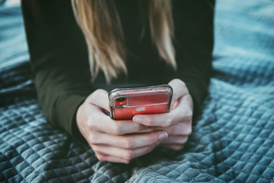 Woman laying down and checking her phone