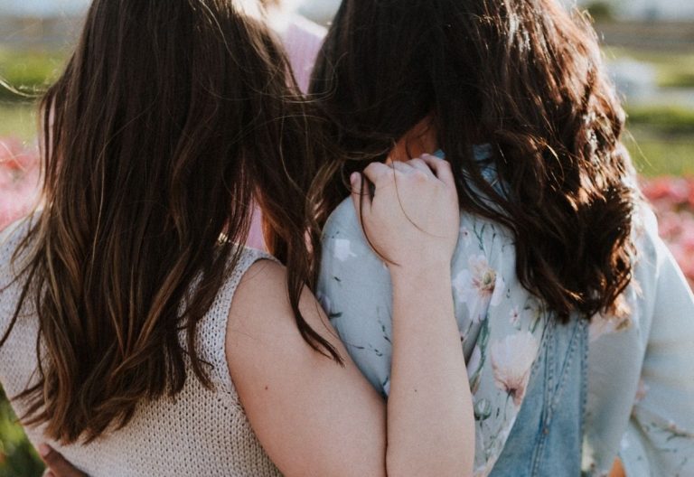 two girls are standing in a field of tulips.