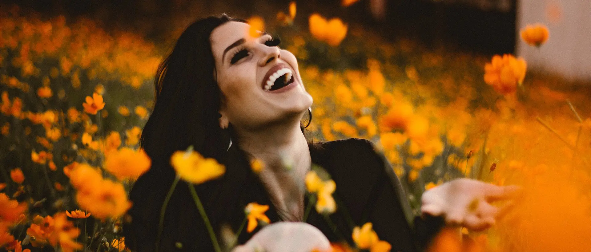 a woman laughing in a field of flowers.