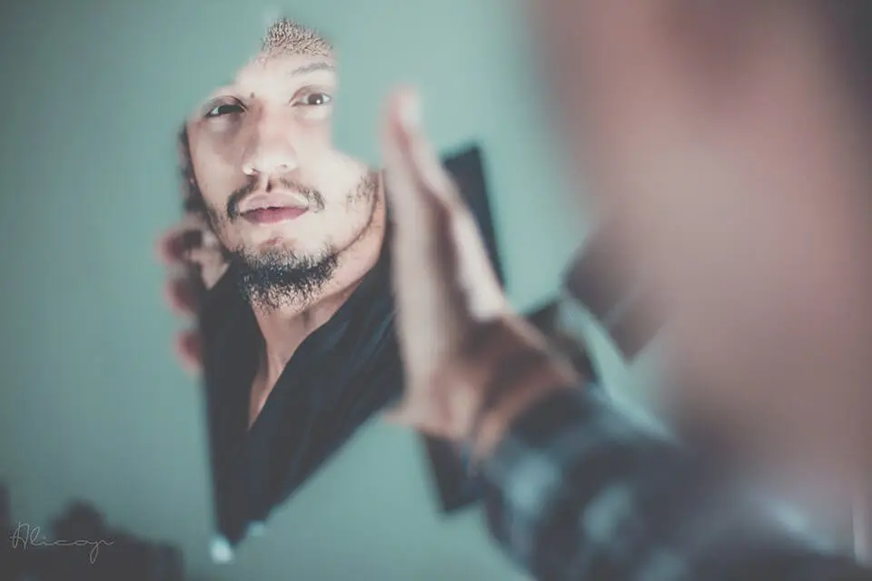 Man looking into shard of mirror