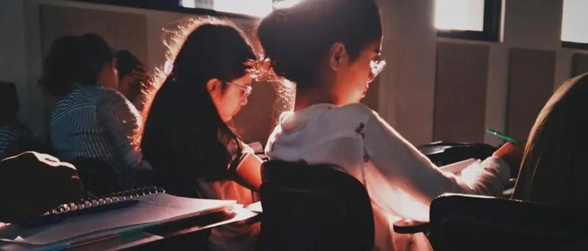 a couple of kids sitting at a desk in front of a laptop computer.