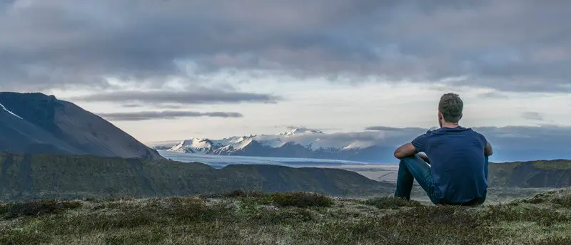 a man sitting on top of a lush green hillside.