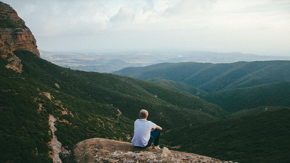 Man sitting on top of hill contemplating