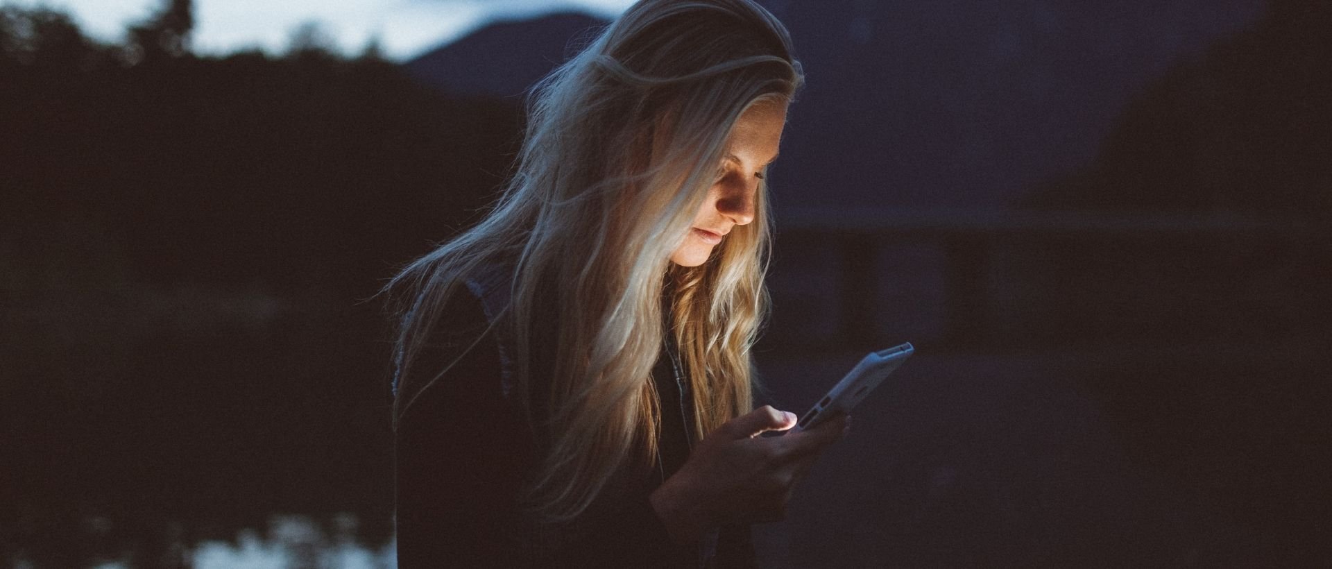 a woman looking at her cell phone in the dark.