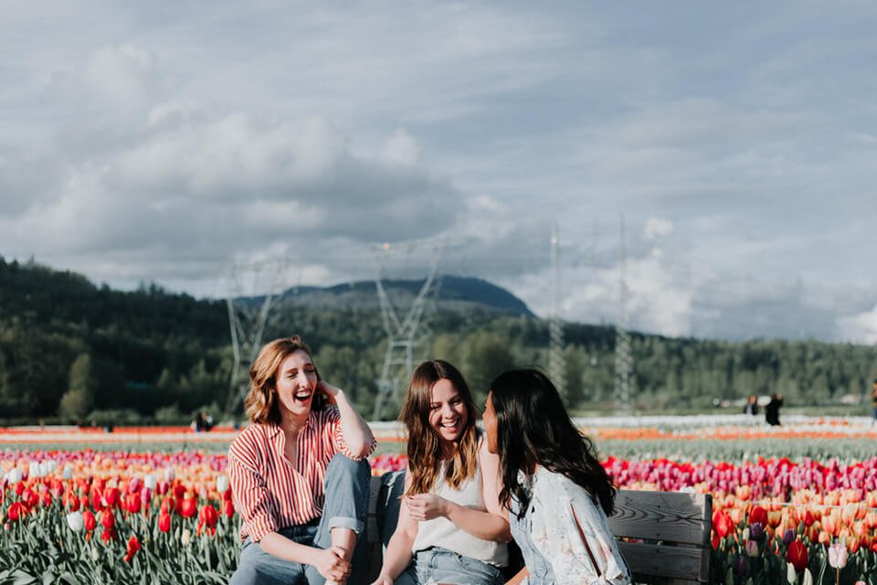 Group of women smiling and lauging on a park bench