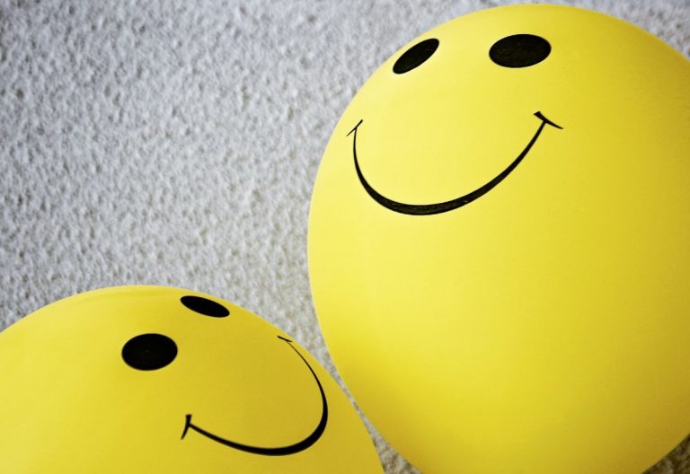 two yellow balloons with faces drawn on them.