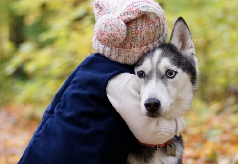 a woman holding a husky dog in her arms.