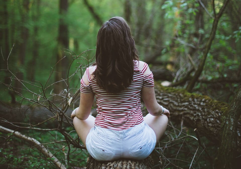 Woman sitting on tree trunk meditating