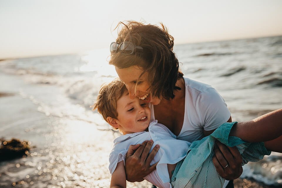 Woman smiling and carry her child on the beach.