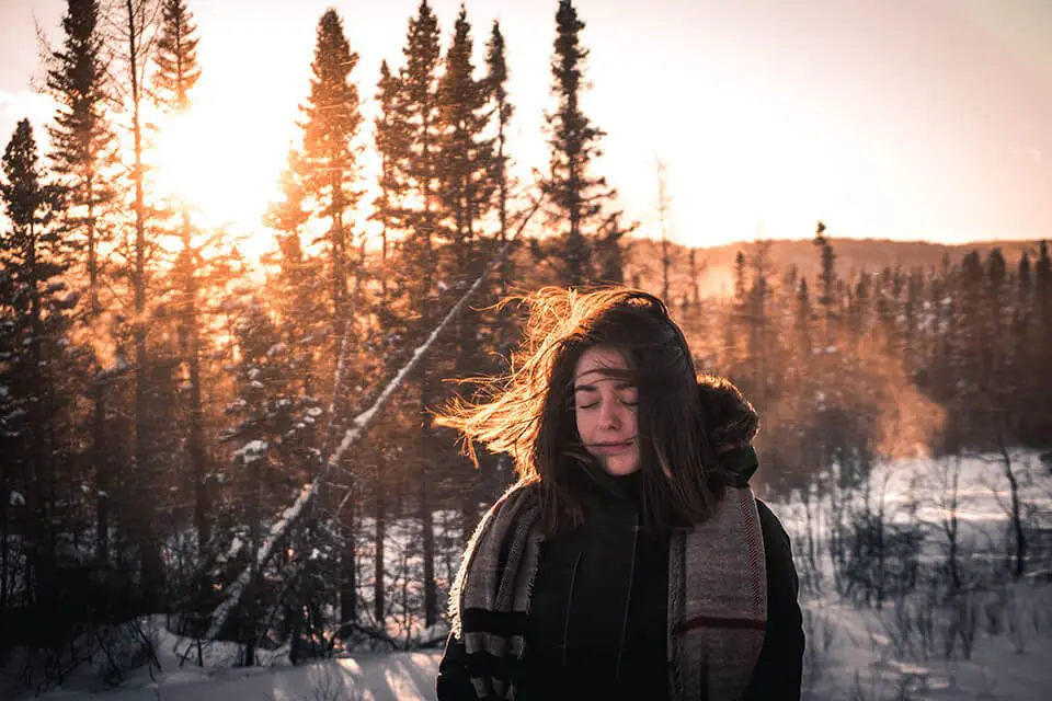 a woman standing in the snow with her eyes closed.