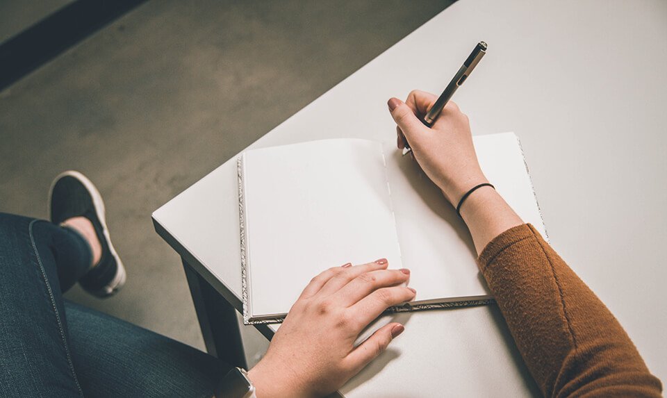 Woman writing her goals down on a pad of paper