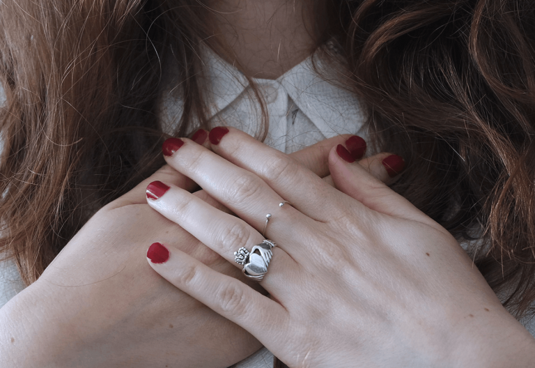 a woman with red nails and a ring on her hand.