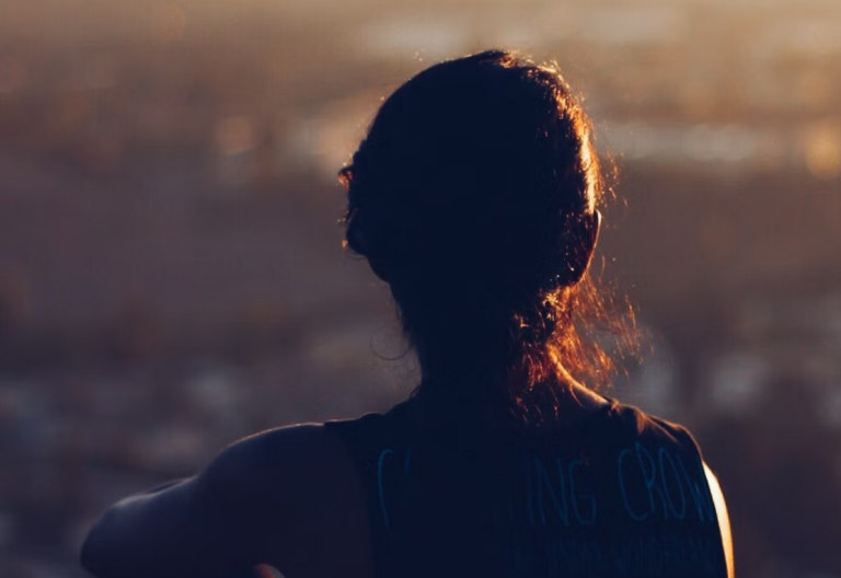 the back of a woman's head with a city in the background.