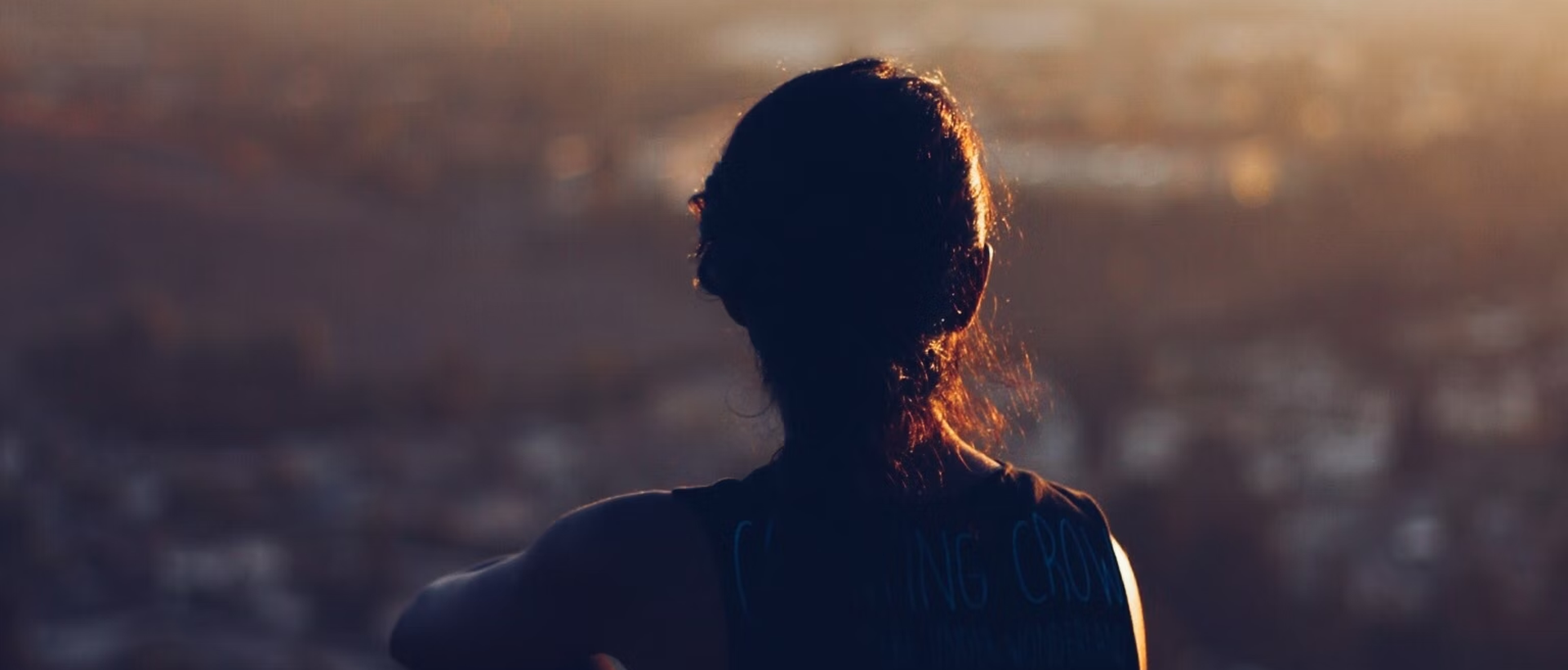 the back of a woman's head with a city in the background.