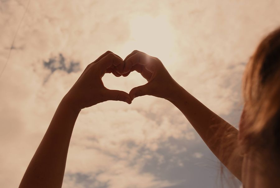 a woman making a heart shape with her hands.