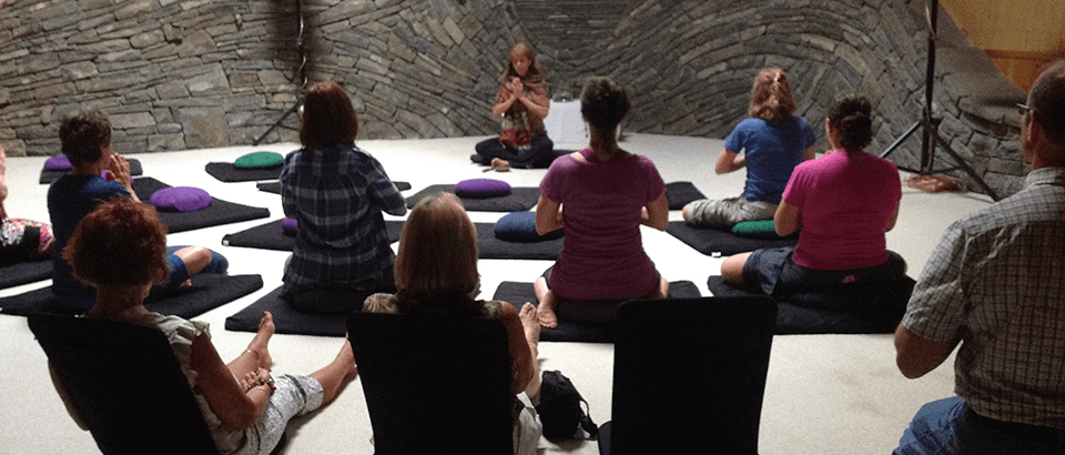 a group of people sitting in a circle doing yoga.