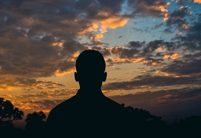 a silhouette of a man in front of a sunset.