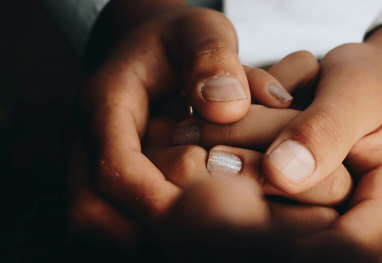 a close up of two people holding hands.